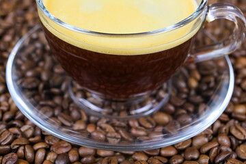 Closeup of isoalted transparent glass cup, saucer and handle with black coffee whitecap crema,...