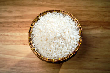 overhead flat lay shot of raw Thai's jasmine rice in Thai's traditional style bamboo's bowl on...