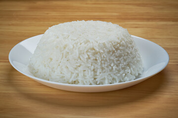 streamed white Thai's jasmine rice in the white clean dish isolated put on the wooden plate dinner table