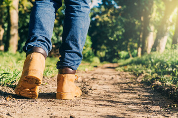 feets of an adult with boots to travel walking in a green forest. travel and hiking concept.