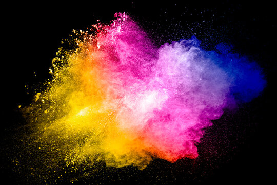 Multicolored particle exploding on black background. Colorful dust splashing.