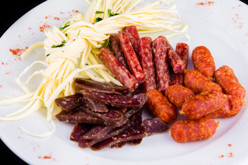 Beer appetizer: cecil cheese, picolini sausages, sujuk, jorki. Plate with delicious sliced smoked sausages