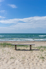 vertical view of a wooden bench on an idyllic secluded empty beach