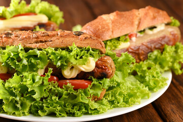 Hot dog with lots green salad and fried sausages.