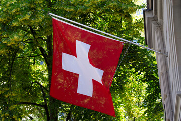 Swiss flag blowing in the wind at famous Bahnhofstrasse at City of Zurich at summertime. Photo...