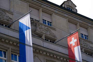 Fototapeta na wymiar Swiss flag blowing in the wind at famous Bahnhofstrasse at City of Zurich at summertime. Photo taken July 1st, 2021, Zurich, Switzerland.