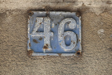 Vintage grunge square metal rusty plate of number of street address with number. Close up, brand.