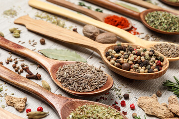 Different natural spices and herbs on light wooden table, closeup