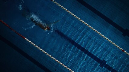 Aerial Top View: Muscular Male Swimmer in Swimming Pool. Professional Athlete Swims in Backstroke Style, Determination to Win Championship. Dark Dramatic Colors, Cinematic Light, Artistic Slow Motion - Powered by Adobe