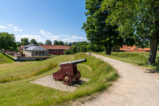 view of the military barracks in the citadel in the center of Copenhagen with an old cannon and gravel footpath in the foreground