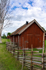 idyllic red shed in the Swedish countryside with an old wooden fence in the foreground