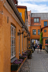 narrow cobblestone street with colorful buildings and many pedestrians in the historic old city center of Koge