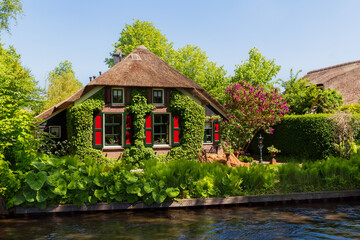 Fototapeta na wymiar Giethoorn, Netherlands, May 30, 2021. The famous village of Giethoorn in the Netherlands with traditional dutch houses, gardens and water canals and wooden bridges is know as 