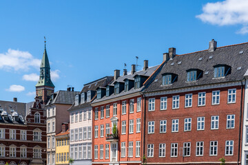 colorful historic cityscape and buildings with a church spire in the background under a blue sky...