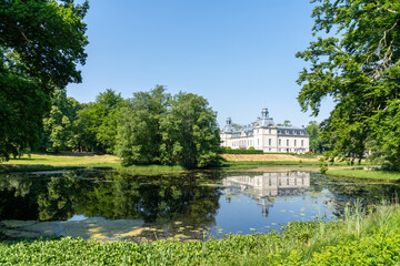 Fototapeta na wymiar picturesque Kronovall Castle and gardens reflected in a pond in the foreground on a summer dday under a blue sky