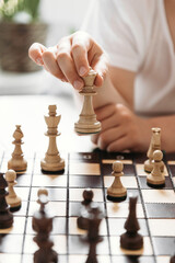 Close-up of a child's hand with a chess piece in hand. Queen move. Chess games and learning for children. Vertical photo