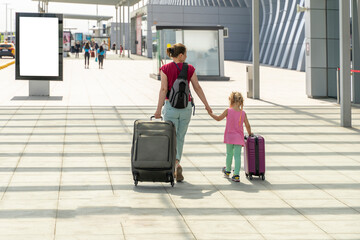 mother and little daughter go with suitcases to the airport. tourism and travel.