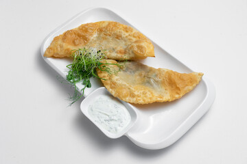 cheburek or fried dough pie with meat feeling and sauce on white background