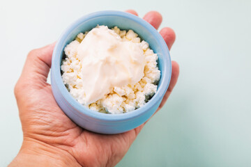 In the palm of your hand is a twogor with sour cream in a blue cup. Morning breakfast.