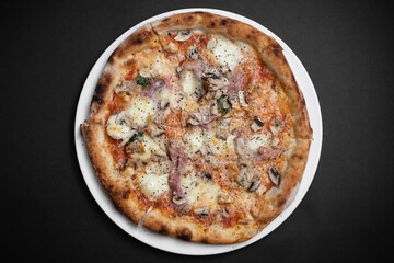 top view of italian pizza with ham, mushrooms and cheese on black background