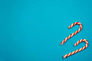 two red and white Christmas lollipops lie on a blue background, top view