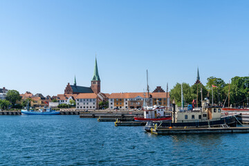 cityscape of the harbor and old town of Helsingor in northern Denmark with colorful fishing boats in the foreground