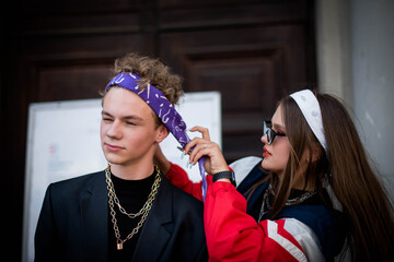 Cute fun curly teenage boy and girl wearing stylish 90s fashion clothes with chains around neck....