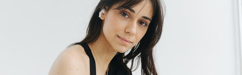 brunette armenian woman in earphone looking at camera on white, banner