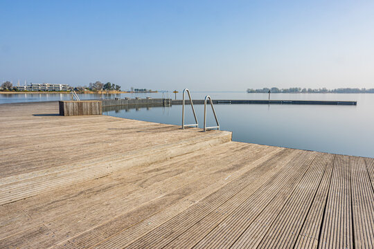 Wooden Platform Or Atoll With Metal Stairs In Natural Swimming Pool At Woldstrand Zeewolde Beach Recreation Area, Spring Day With Light Fog In Flevoland, Netherlands