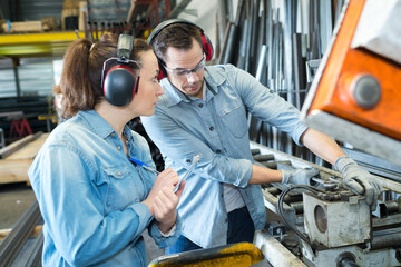 couple of happy adult workers are working around a machine