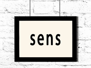 Black frame hanging on white brick wall with inscription sens © iushakovsky