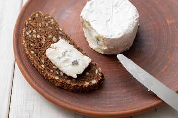 Grain bread and blue cheese on a brown clay plate. Cooking snacks.