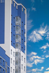 A fragment of the facade of a residential building against a blue sky with white clouds