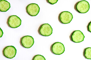 repeating pattern of sliced semicircles of fresh raw vegetable cucumbers for salad isolated on a white background flat lay, top view
