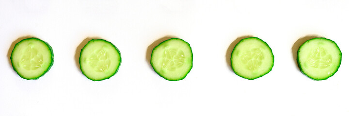 repeating pattern of sliced semicircles of fresh raw vegetable cucumbers for salad isolated on a white background flat lay, top view. banner