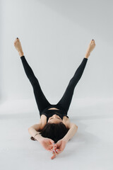 barefoot armenian woman in black leggings practicing yoga in rejuvenation pose on white