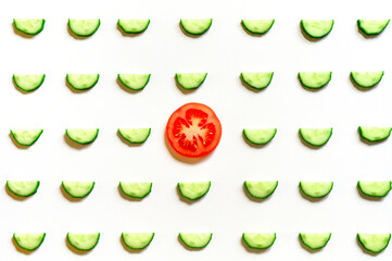 repeating pattern of sliced semicircles of fresh raw vegetable cucumbers for salad and a slice of tomato in the center isolated on a white background flat lay, top view