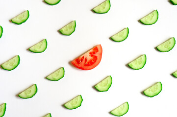 repeating pattern of sliced semicircles of fresh raw vegetable cucumbers for salad and a slice of tomato in the center isolated on a white background flat lay, top view