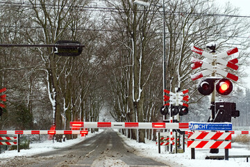 Closed snowy rail crossing with red signals in winter, the Netherlands