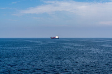 Obraz premium large freight ship travelling full steam ahead and approaching from far away on the open ocean