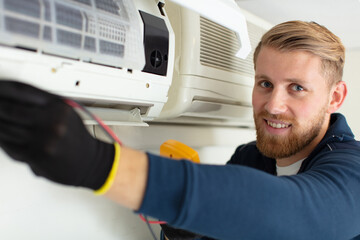 young male technician cleaning air conditioning system at home