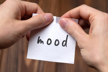 Hands tearing off paper with inscription mood