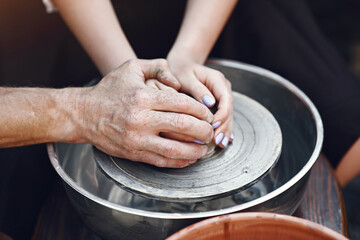 People making a vaze from a clay on a pottery's machine