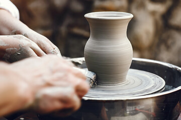 People making a vaze from a clay on a pottery's machine