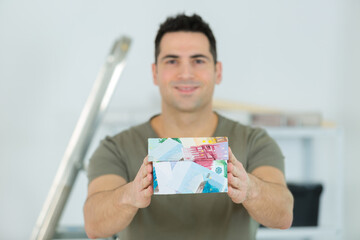 man hlding a model house made from banknotes