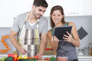 couple in home kitchen using electronic tablet