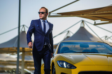Successful yang businessman in yellow cabrio car.