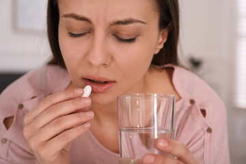 Sad young woman taking abortion pill at home, closeup
