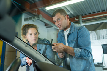 man and woman workier during car windshield replacement