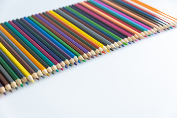 Set of colored watercolor pencils arranged in a diagonal isolated on a white background. View from above